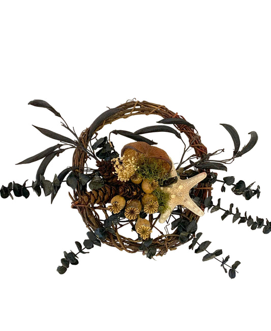 Decorative wreath with black leaves, pinecones, and a starfish on a white background
