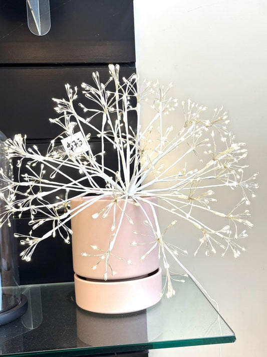 Decorative LED plant on a glass surface with a neutral background